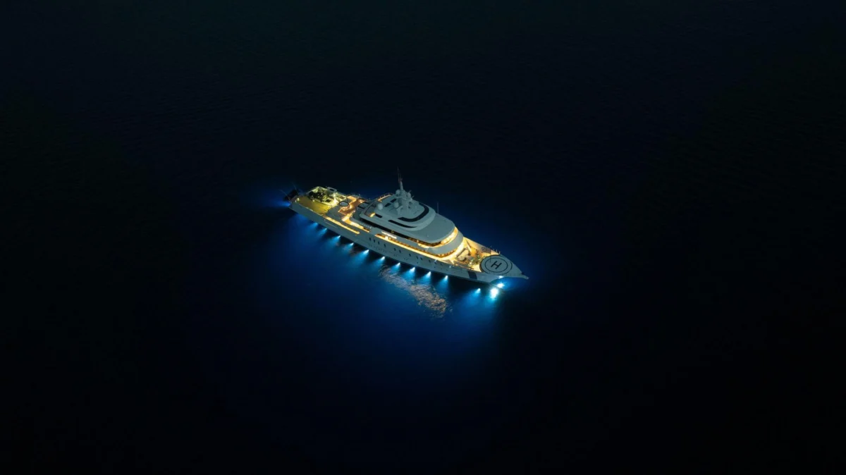 Aerial view of a superyacht at night with underwater and deck lighting